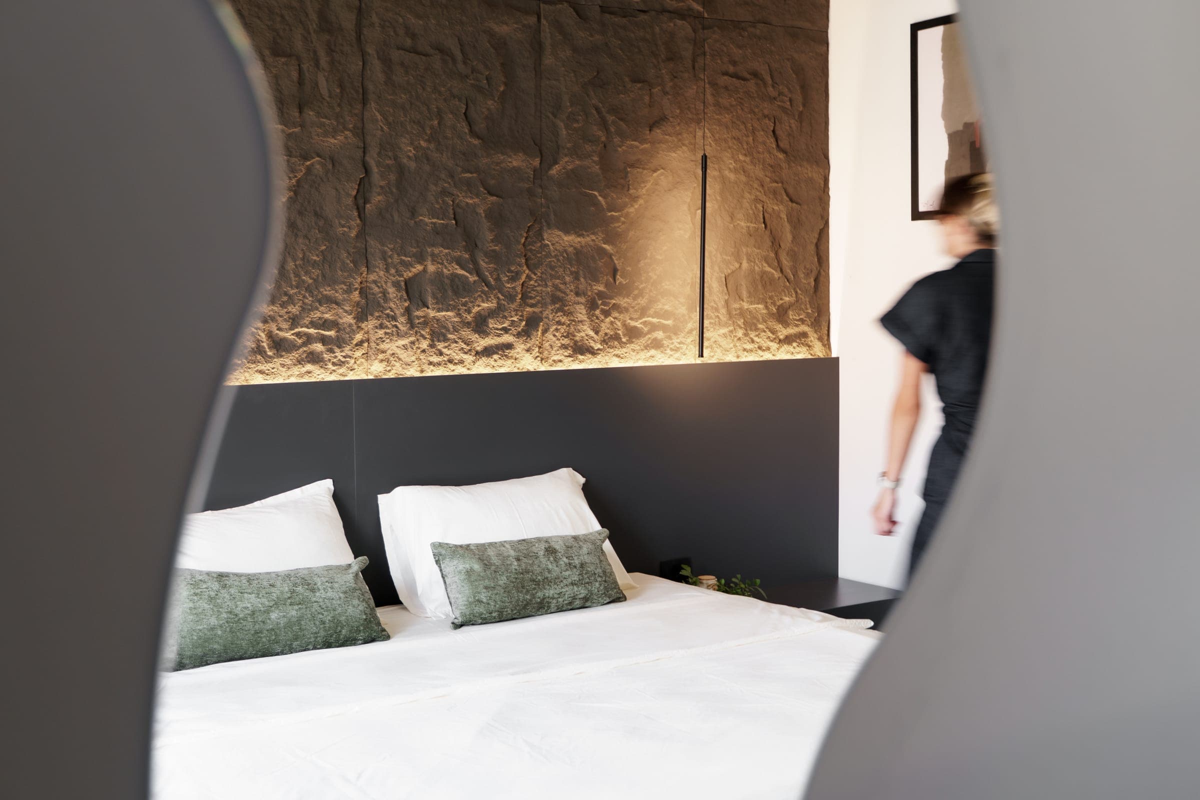 Bedroom with a textured dark feature wall and warm concealed lighting