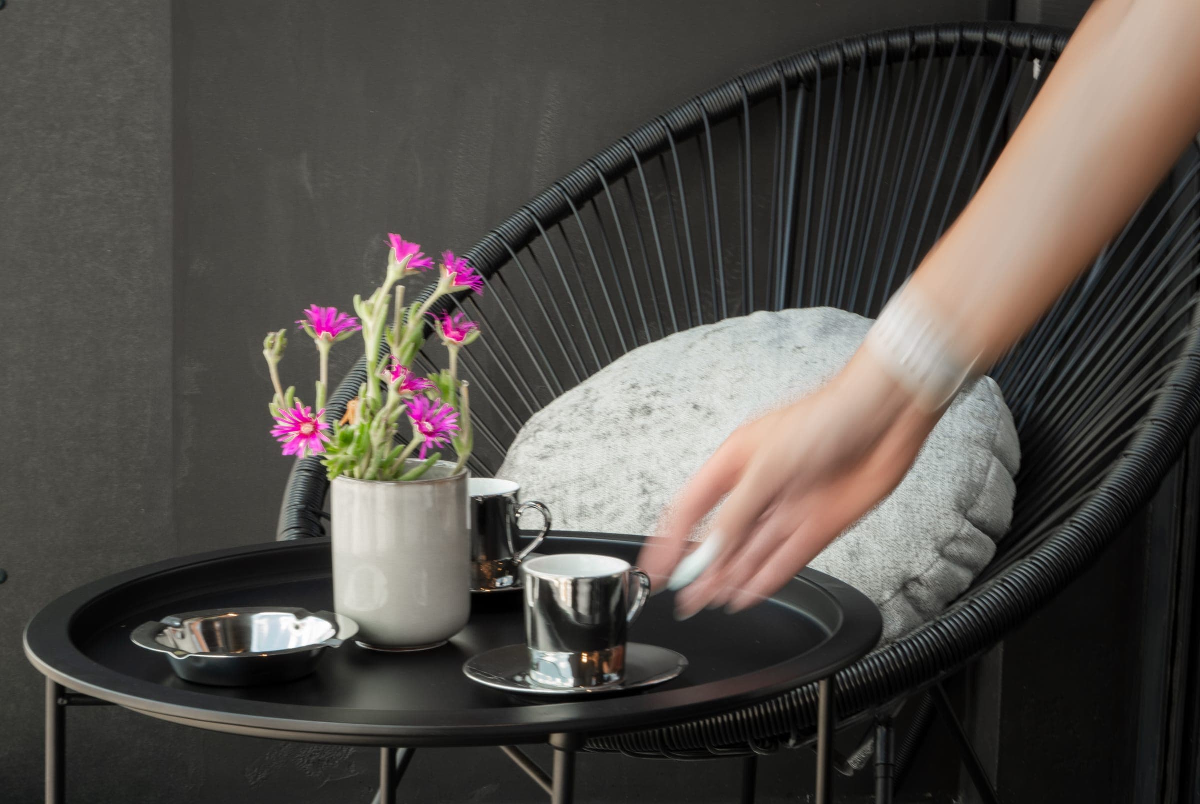 Black wire lounge chair with a coffee tray and flowers
