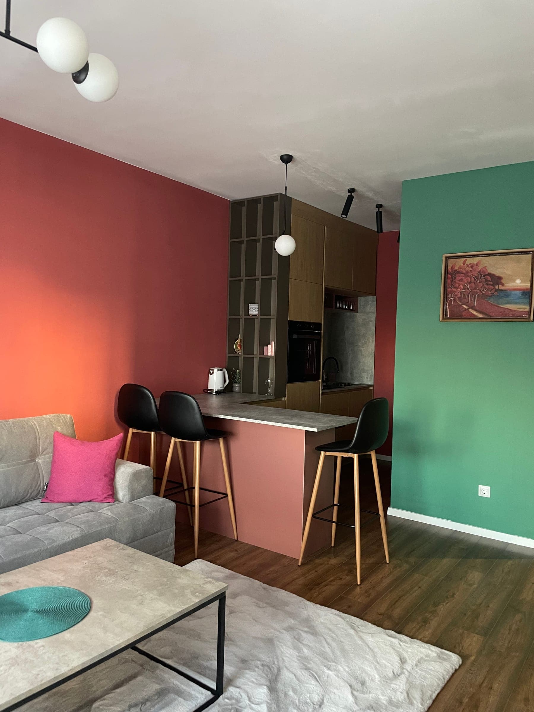 Open living area with coral and sage green walls, the kitchen bar and the lounge
